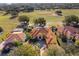 Expansive aerial view of a custom home with a tile roof overlooking a lush golf course and mature trees at 2313 Roat Dr, Orlando, FL 32835