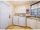 Well-lit laundry room includes modern washer and dryer, utility sink, ample storage, and a sunlit window at 2313 Roat Dr, Orlando, FL 32835