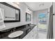 Bright bathroom featuring a double vanity with a black granite countertop and black and white tiled floors at 3117 Lake Mar Ln, Orlando, FL 32806