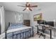 Bedroom featuring a ceiling fan, a bed with blue patterned covers, a dresser, and a desk with computer monitors at 3117 Lake Mar Ln, Orlando, FL 32806
