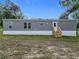 Grey home with a small porch and yard, set against a backdrop of lush trees at 5045 Se 148Th St, Summerfield, FL 34491