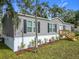 Gray home with black shutters, a white door, and well-maintained landscaping at 5045 Se 148Th St, Summerfield, FL 34491