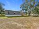 Grey home featuring an expansive yard, a small porch, and several mature trees at 5045 Se 148Th St, Summerfield, FL 34491