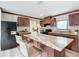 Well-lit kitchen with dark wood cabinets, an island with seating, and modern appliances at 5045 Se 148Th St, Summerfield, FL 34491