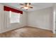 Bedroom with wood-look floors, one large window with curtains and an overhead fan with light fixture at 5852 Mariposa Cove Ln, Orlando, FL 32822