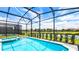 Beautiful screened-in pool overlooking a serene lake with lush landscaping at 7219 Oakmoss Loop, Davenport, FL 33837