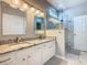 Bright bathroom boasts a dual sink vanity with granite counters and a seamless glass shower at 7709 Comrow St, Kissimmee, FL 34747
