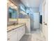 Bright bathroom boasts a dual sink vanity with granite counters and a seamless glass shower at 7709 Comrow St, Kissimmee, FL 34747