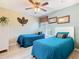 Charming bedroom featuring two twin beds with blue quilts and a ceiling fan at 7709 Comrow St, Kissimmee, FL 34747