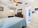 Well-lit bedroom with an open doorway to the bathroom, TV, ceiling fan, and light wood floors at 7709 Comrow St, Kissimmee, FL 34747