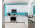 Modern kitchen featuring white cabinetry, stainless steel appliances, granite countertops and turquoise accent wall at 7709 Comrow St, Kissimmee, FL 34747