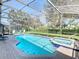 Covered lanai featuring a sparkling pool and a jacuzzi tub surrounded by brick pavers and greenery at 7709 Comrow St, Kissimmee, FL 34747