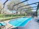 A screened-in pool with brick patio and views of lawn and trees create a perfect backyard oasis at 7709 Comrow St, Kissimmee, FL 34747