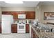 Bright kitchen featuring granite counters, white appliances, a breakfast bar, and wood cabinetry at 8762 Worldquest Blvd # 6506, Orlando, FL 32821