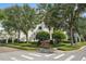 View of The Cloisters community entrance featuring a sign, lush landscaping, trees, and the building's exterior at 100 S Interlachen Ave # 304, Winter Park, FL 32789