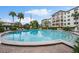 Community pool with patio seating and building exterior with palm trees and the American flag at 100 S Interlachen Ave # 304, Winter Park, FL 32789
