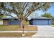 Charming single-story home featuring a bright yellow front door, stone accents, mature tree, and a two-car garage at 1005 Leeds Ct, Winter Park, FL 32792