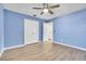 A blue bedroom features a ceiling fan, wood-look floors, and a closet with folding doors at 1008 Birkdale Trl, Winter Springs, FL 32708