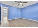 A blue bedroom features a ceiling fan, wood-look floors, and a doorway to another room at 1008 Birkdale Trl, Winter Springs, FL 32708