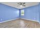 A bedroom with striking blue walls, wood-look floors, a ceiling fan, and a window providing natural light at 1008 Birkdale Trl, Winter Springs, FL 32708