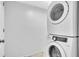 A white stacked washer and dryer unit is seen against a white wall in the laundry area at 1008 Birkdale Trl, Winter Springs, FL 32708