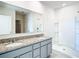 Bright bathroom featuring double sink vanity with granite countertop and a white-tiled walk-in shower at 1133 August Sky Dr, Deltona, FL 32738