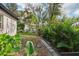 Lush backyard featuring a stone pathway surrounded by mature tropical plants and green grass at 1222 Shorecrest Cir, Clermont, FL 34711