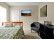 Bright bedroom with a chair, twin bed with a patterned blanket, and a wall-mounted TV at 131 Sonja Cir # 1, Davenport, FL 33897