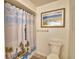 Bright bathroom featuring a toilet, shower with lighthouse-themed curtain, and beachy wall decor at 16 Cedar Dr, Davenport, FL 33837