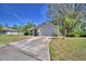 Well-maintained home with a spacious driveway, manicured lawn, and mature trees at 16 Cedar Dr, Davenport, FL 33837