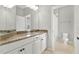 Bathroom with granite counters, double vanity, and white cabinets with tan tile flooring at 16548 Caravaggio Loop, Montverde, FL 34756