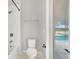 Bright bathroom featuring white tub, toilet, and tile, with a window view of the pool area at 16548 Caravaggio Loop, Montverde, FL 34756
