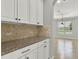 A close up of the white cabinets and granite countertop with views to the living area at 16548 Caravaggio Loop, Montverde, FL 34756