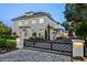 Stunning, light-colored, two-story home featuring manicured landscaping and a gated entrance at 1660 Palmer Ave, Winter Park, FL 32789