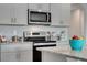 Close up of stainless steel range and microwave surrounded by stone countertops and white cabinets at 1736 Three Bars Rd, Kissimmee, FL 34744
