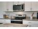 Close up of kitchen with stainless steel microwave and oven with stone countertops and white cabinets at 1736 Three Bars Rd, Kissimmee, FL 34744