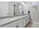 This spacious bathroom features a double vanity with a granite countertop and ample lighting at 1763 White Feather Loop, Oakland, FL 34787