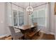 Dining area boasts a rustic wooden table, modern lighting, and large windows with patterned curtains at 1763 White Feather Loop, Oakland, FL 34787