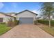 Attached gray garage with wide driveway, with lovely front yard landscaping at 1763 White Feather Loop, Oakland, FL 34787