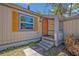 Close-up of a cozy front porch featuring an orange front door, gray trim and stone steps at 525 S Crystal Lake Dr, Orlando, FL 32803