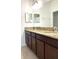 Bathroom with double granite countertop vanity, dark wood cabinets, and large mirrors at 7681 Fordson Ln, Windermere, FL 34786