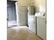 Tile laundry room area with modern washer, dryer, shelving, and exterior access at 7681 Fordson Ln, Windermere, FL 34786