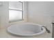 Bright bathroom featuring a soaking tub beneath a window with white tile surround at 8519 Rainbow Ave, Orlando, FL 32825
