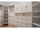Walk-in closet with custom white cabinets and shelving with metal handles and hardwood floors at 9454 Becker Ct, Orlando, FL 32827