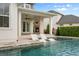 Luxurious outdoor space featuring a pool with in-water loungers, covered patio and stone fireplace at 9454 Becker Ct, Orlando, FL 32827