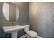 Stylish powder room featuring a pedestal sink, round mirror, and decorative wallpaper at 9454 Becker Ct, Orlando, FL 32827