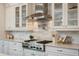 Gourmet kitchen featuring a stainless steel stove, range hood, and white cabinetry at 9454 Becker Ct, Orlando, FL 32827