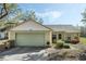 View of house with attached garage, grill, walkway and garden with a beautiful blue sky backdrop at 10320 Bumblebee Ln, Leesburg, FL 34788