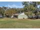 Backyard view of home with large lawn and mature trees creating a private setting at 10320 Bumblebee Ln, Leesburg, FL 34788