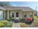 Inviting front door, featuring a lovely garden with a charming wheelbarrow filled with vibrant flowers and a paved walkway at 10320 Bumblebee Ln, Leesburg, FL 34788
